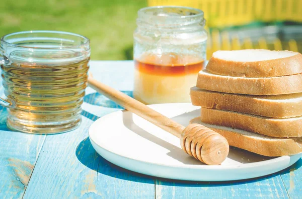 tea with honey and the cut white pastries slices on a wooden blue table background. Tea with honey in a summer garde