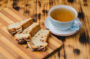 Çay fincanı ve masada dilimlenmiş hamur işleriyle kahvaltı. Seçici odak