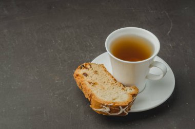 Beyaz çay fincanı ve pastalar koyu taş masada. Temeliniz için kopyalanma alanı