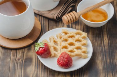 Çay, bal ve taze çilekle süslenmiş gofretlerle nefis bir kahvaltı. Üst görünüm