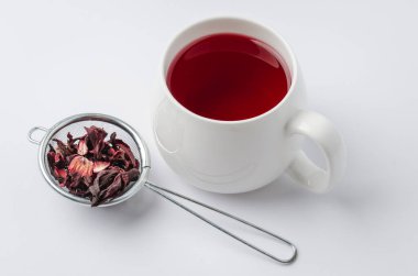 Beyaz fincanda kırmızı amber çayı ve beyaz arka planda izole edilmiş kuru çiçek, seçici odak