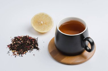 Bambu destekli, siyah bardakta meyve çayı, limon dilimi ve beyaz arka planda izole edilmiş kurutulmuş çay.