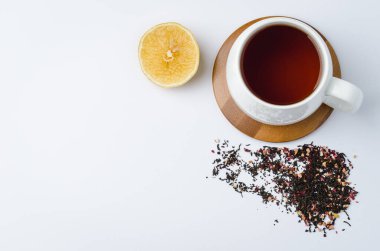 Bambu destekli beyaz fincanda meyve çayı, limon ve kuru çay beyaz arka planda izole edilmiş. Kopyalama alanı ve üst görünüm
