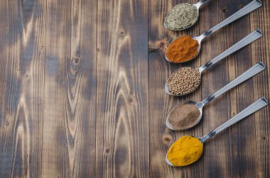 Ahşap bir masada çeşitli aromatik baharatlar seti. Üst görünüm ve telif alanı. Yemek pişirmek için gerekli malzemeler