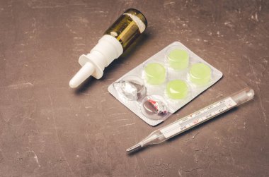 Drug spray bottle, pills packages and thermometer on black background/Drug spray bottle, pills packages and thermometer. Medicine subject. Top view.