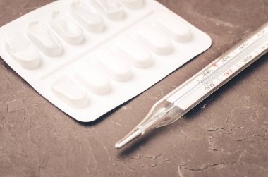 Siyah arkaplan üzerindeki hap paketleri ve termometre / haplar ve termometre siyah arkaplana yerleştirilir.