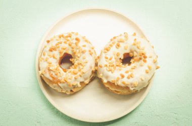Donat. Donata 'dan beyaz jöleli fındıklı bir tabak. Üst Manzara. Taze hamur işleri. Tatlı yemek konsepti.