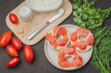 Healthy breakfast with round toast, red fish, vegetables and cheese/cooking of a breakfast with round toast with cheese, red fish, tomatoes and vegetables on stone table. Top view.