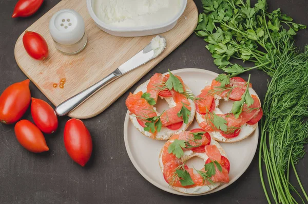 Healthy breakfast with round toast, red fish, vegetables and cheese/cooking of a breakfast with round toast with cheese, red fish, tomatoes and vegetables on stone table. Top view.