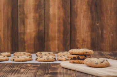 Kabartma kağıdı ve ahşap masa üzerinde çikolatalı kurabiyeler. Kabartma kağıdı ve ahşap masa üzerinde çikolatalı kurabiyeler. Taze hamur işleri. Boşluğu kopyala.
