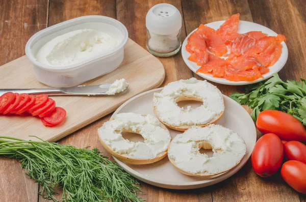 Healthy breakfast with round toast, red fish, vegetables and cheese/cooking of a breakfast with round toast with cheese, red fish, tomatoes and vegetables