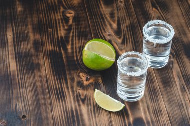 kireç dilimli iki tekila shot ve ahşap masaya tuz, tekila shot ve kopya cpace ile ahşap masaya limon dilimi. Üst görünüm.