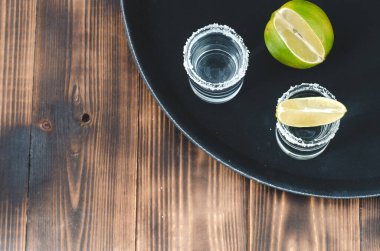 kireç dilimli iki tekila shot ve ahşap masaya tuz, tekila shot ve kopya cpace ile ahşap masaya limon dilimi. Üst görünüm.
