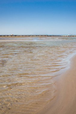 Mavi gökyüzü olan boş bir kumsalın güzel deniz manzarası Denizde boş bir yaz plajı ve güneşli bir gökyüzü
