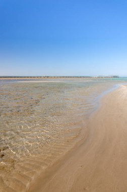 Mavi gökyüzü olan boş bir kumsalın güzel deniz manzarası Denizde boş bir yaz plajı ve güneşli bir gökyüzü