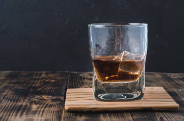 Ahşap bir çubuk üzerinde buz küpleri olan bir bardak konyak. Arka planda kopyalanmış ahşap bir çubukta buz küpleri olan bir bardak konyak.