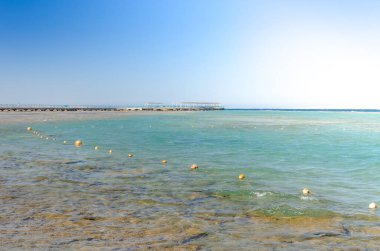 Mavi gökyüzü olan boş bir kumsalın güzel deniz manzarası Denizde boş bir yaz plajı ve güneşli bir gökyüzü