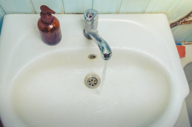 Sabun aksesuarlı lavabo, sabun makineli lavabo ve kozmetik şişeli banyo.