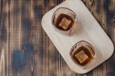 Ahşap bir masada buz küplü iki bardak viski / Ahşap bir masada buz küplü iki bardak konyak. Üst görünüm, kopyalama alanı