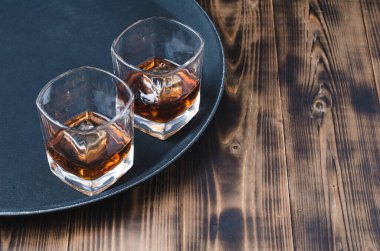 Siyah tepside buz küplü viski ve ahşap masa. Siyah tepside buz küpleri olan iki bardak viski ve kopyalanmış ahşap masa..