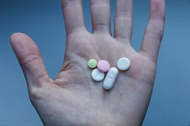 Çok renkli tablet. Mavi bir arka plan üzerinde bir kadın birkaç farklı uyuşturucu haplarla el.