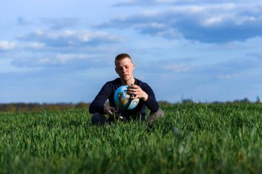 Adam yeşil tarlada oturuyor ve Dünya 'ya bakıyor.