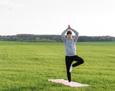 Yeşil alanda meditasyon yapan adam dengeyi koruyor.