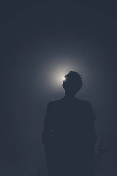 Silhouette of a person with sun behind causing sun eclipse effect.