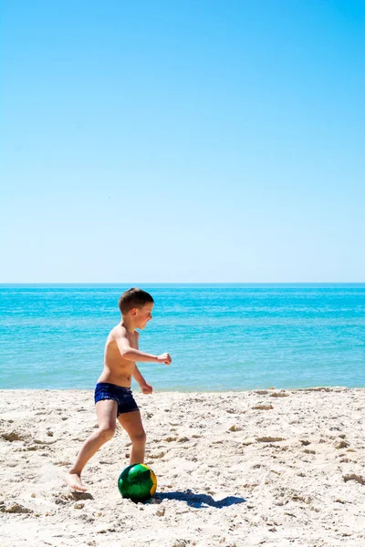 Мальчик играет в футбол на пляже — стоковое фото