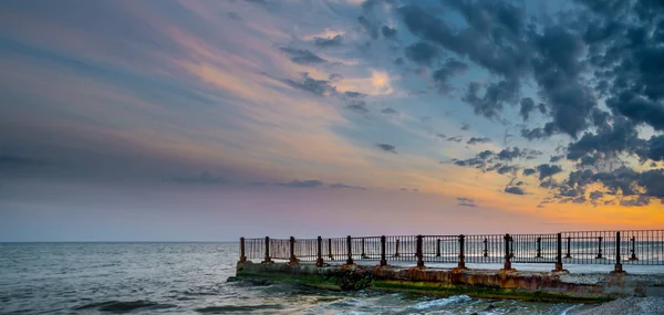 Old pier on background of sunset on beach — Stock Photo, Image