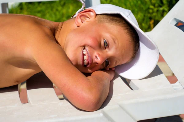 Happy boy lying on deck chair at the beach — Stock Photo, Image