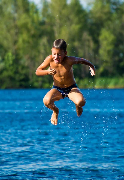 Jeune garçon sautant dans l'eau — Photo