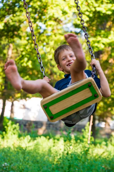 Bonito menino da escola desfrutando de um passeio de balanço — Fotografia de Stock