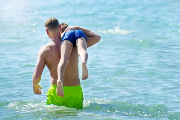 年轻男子携带他的儿子在夏季海、 copyspace 右边肩膀上 — 图库照片