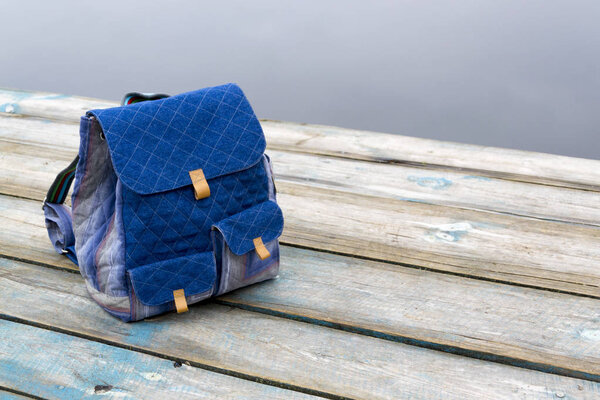 Рюкзак на деревянном пирсе в водный путь в облачный день
.