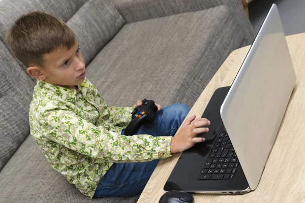 Menino jogando jogos de vídeo com joystic sentado no sofá — Fotografia de Stock