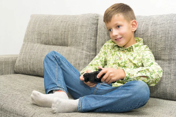 Pojke spela videospel med joystic sitter på soffa — Stockfoto