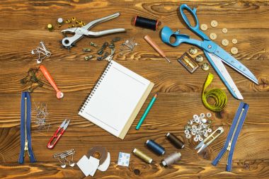 Boş defter ve dikiş araçlar ahşap dokulu arka plan üzerinde boşluk.