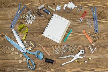 Boş defter ve dikiş araçlar ahşap dokulu arka plan üzerinde boşluk.