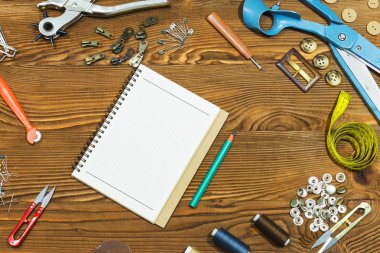 Boş defter ve dikiş araçlar ahşap dokulu arka plan üzerinde boşluk.