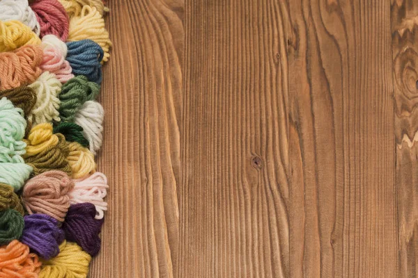 Barevné pletení vlákna na dřevěné pozadí — Stock fotografie
