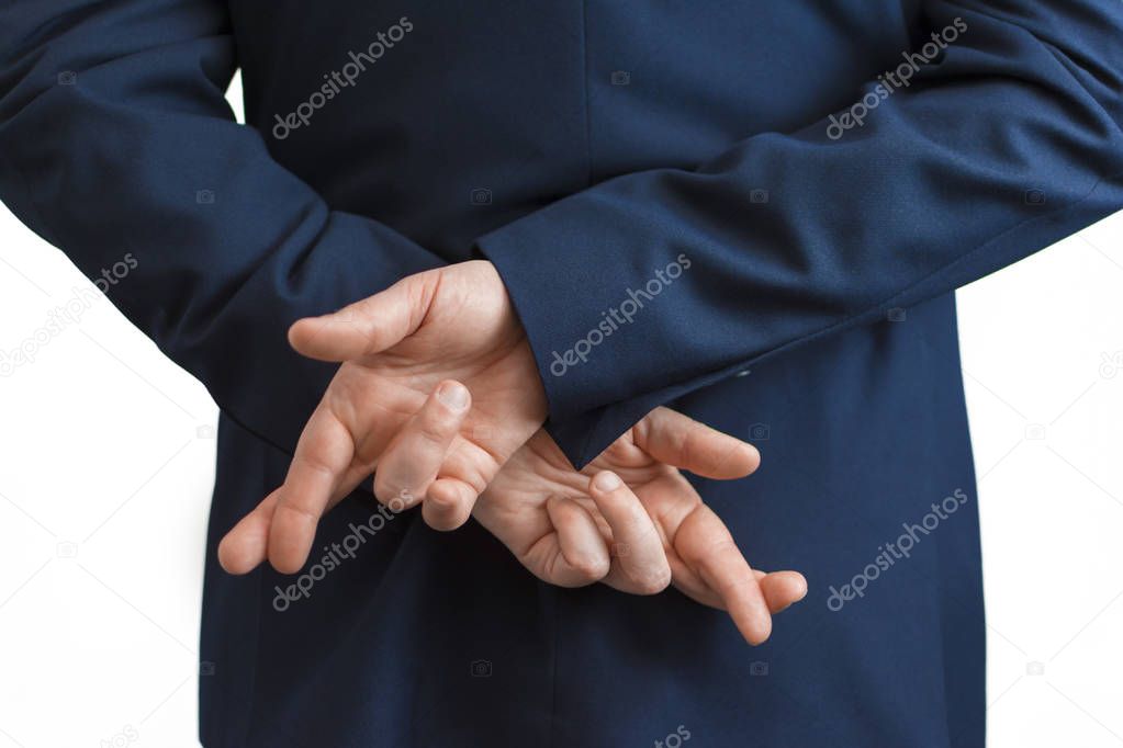 Closeup of a business man with his hands behind his back and fingers crossed.