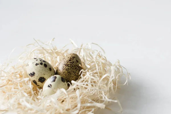 Easter greeting card Quail eggs in hay nest on white wooden background. — Stock Photo, Image