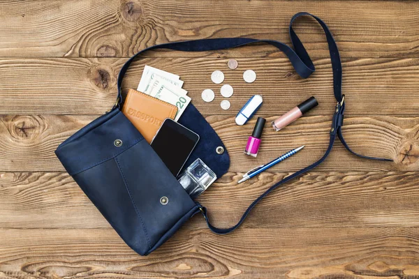 Κοντινό πλάνο Γυναίκα τσάντα ανοίγουν με διαβατήριο, ακουστικά, αξεσουάρ smartphone, δολάρια σε φόντο ξύλινη κορυφή άποψη, επίπεδη lay — Φωτογραφία Αρχείου