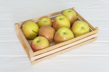 Ahşap sandık kutu dolu taze elma beyaz masaya izole.