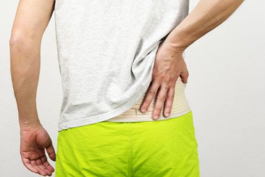 giyen arka destek kemer altında onun T-shirt ve hasta geri tutan adam