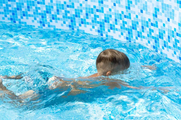 Criança aprende a nadar, mergulhar na piscina azul com diversão - pulando no fundo debaixo d 'água com salpicos . — Fotografia de Stock