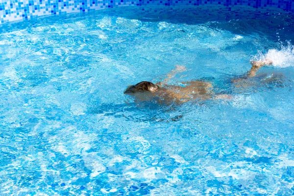 Child learn to swim, dive in blue pool with fun - jumping deep down underwater with splashes.