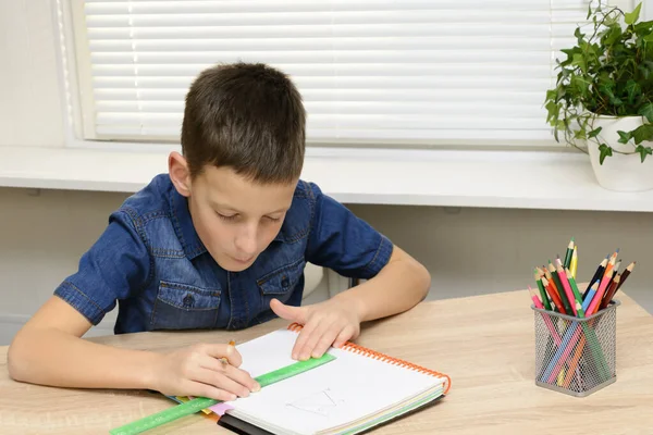 少年は、ノートブックに描画します。家の机に座って、彼の宿題をしている子。学校、子供、教育の概念 — ストック写真