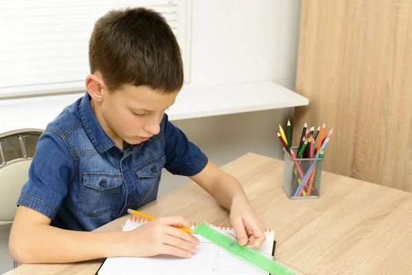 少年は、ノートブックに描画します。家の机に座って、彼の宿題をしている子。学校、子供、教育の概念 — ストック写真